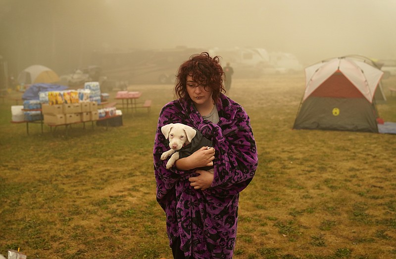 Shayanne Summers holds her dog Toph while wrapped in a blanket after several days of staying in a tent at an evacuation center at the Milwaukie-Portland Elks Lodge, Sunday,in Oak Grove, Ore. "It's nice enough here you could almost think of this as camping and forget everything else, almost," said Summers about staying at the center after evacuating from near Molalla, Oregon which was threatened by the Riverside Fire. - AP Photo/John Locher