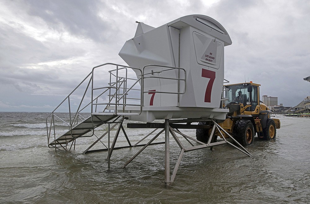 A lifeguard stand is removed from a flooded beach in Pensacola Beach, Monday, Sept. 14, 2020. Storm-weary Gulf Coast residents rushed to finish last-minute preparations Monday as Hurricane Sally chugged slowly through warm Gulf waters. Forecasters predicted the biggest threat is flooding, with as much as two feet of rain falling in some areas. (Tony Giberson/Pensacola News Journal via AP)