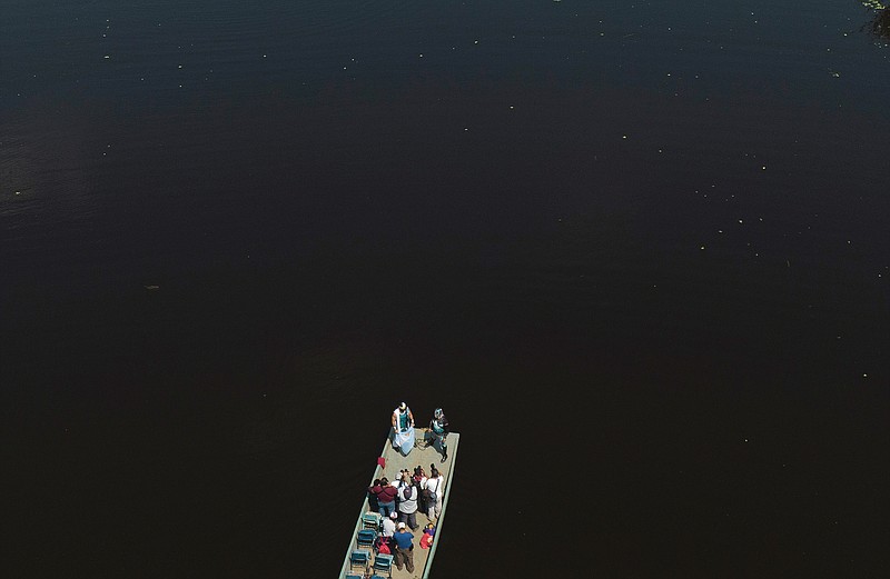 Mexican Lucha Libre wrestlers stand at the edge of a boat where photographers take their picture prior to an exhibition fight for the media, as part of training for what will be live streaming events which they charge for, at Xochimilco's famous floating gardens on the outskirts of Mexico City, Saturday, Aug. 22, 2020. While wrestling halls are closed amid the new coronavirus pandemic, some wrestlers are trying to take the sport online, with matches on pay-per-view, and other wrestlers have taken to street vending to make a living. (AP Photo/Fernando Llano)