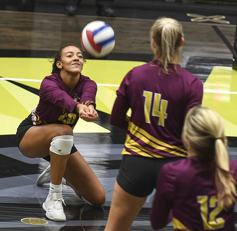 Lake Hamilton junior Audri Winfrey (20) digs the ball as senior teammates Aryn Hughes (14) and Kynzee Dixon (12) look on in Tuesday’s 3-1 win over Hot Springs in Trojan Arena. - Photo by Grace Brown of The Sentinel-Record story.lead_photo.caption