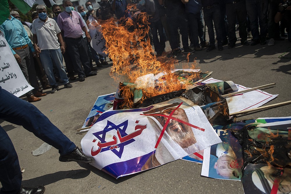 Palestinians burn pictures of U.S. President Donald Trump, Israeli Prime Minister Benjamin Netanyahu, Bahrain's King Hamad bin Isa Al Khalifa and and Abu Dhabi Crown Prince Mohammed bin Zayed al-Nahyan, during a protest against the United Arab Emirates and Bahraini normalization agreement with Israel, in Gaza City, Tuesday, Sept. 15, 2020. Israel is set to sign agreements with the UAE and Bahrain at the White House on Tuesday. Arabic on poster with representation of an Israeli flag reads, "traitor." (AP Photo/Khalil Hamra)