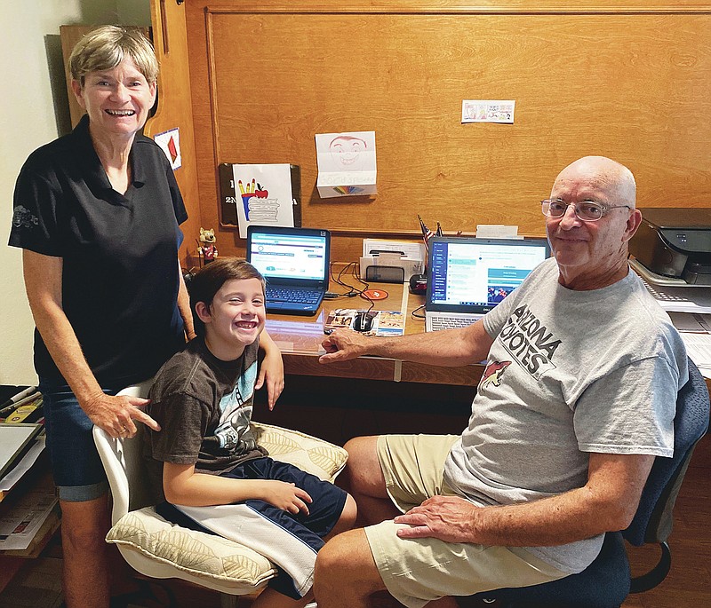 This image released by Bill Hill shows Mary Hill, left, and her husband Bill, right, with their 8-year-old grandson in suburban Phoenix. The 72-year-old Bill, a former college sports administrator, and 70-year-old Mary, who worked as a nurse practitioner, volunteered to keep Will five days a week and oversee distance learning after their son and daughter-in-law were required to report in person to the school where they teach. (Bill Hill via AP)