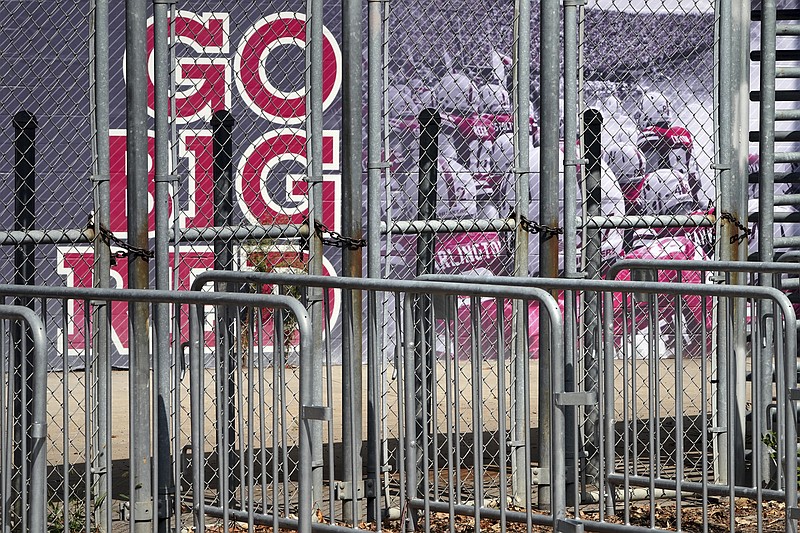 A mural showing Nebraska football players and Go Big Red lettering are seen past locked gates at Memorial Stadium in Lincoln, Neb., Tuesday. - Photo by Nati Harnik of The Associated Press story.lead_photo.caption