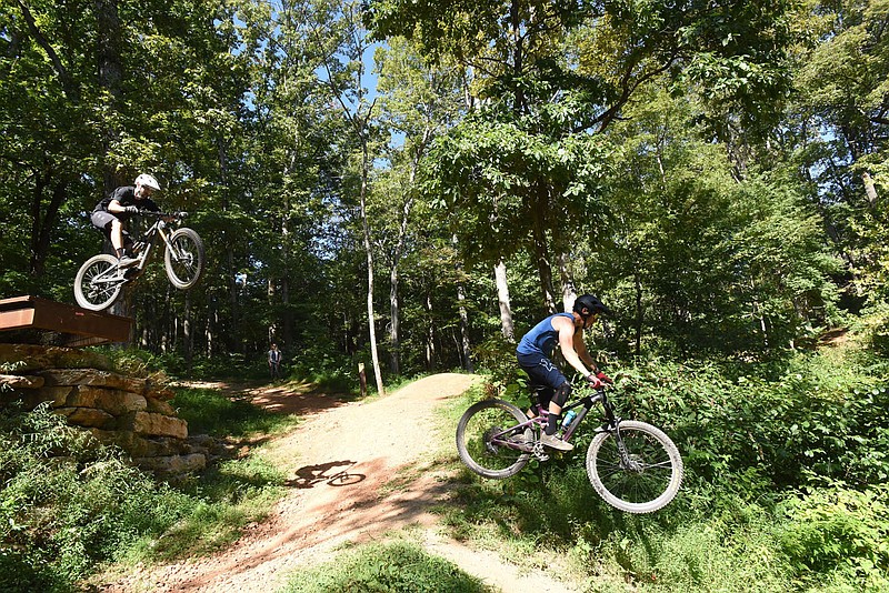 The preserve has 18 miles of mountain bike trails for beginner to expert riders. Jerry Hill (left) and Craig Wohlschlager, both of Bentonville, fly over a jump at the mountain bike preserve.
(NWA Democrat-Gazette/Flip Putthoff)