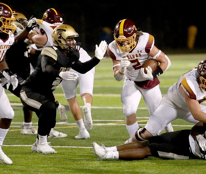 Lake Hamilton’s Owen Miller (2) heads through a hole for yardage as Hot Springs’ Anthony Island (4) defends during first half action at Hot Springs Thursday. The Wolves took a 38-28 win over the Trojans. - Photo by Richard Rasmussen of The Sentinel-Record