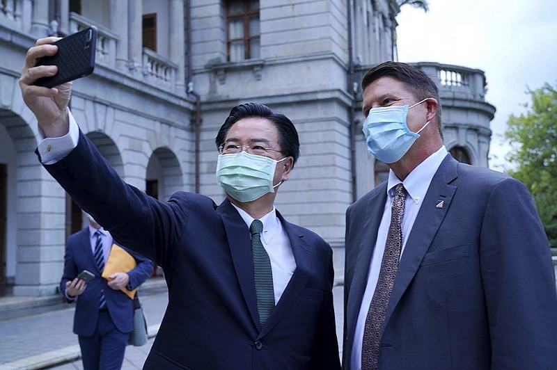 In this photo released by the Taiwan Ministry of Foreign Affairs, Taiwan's Foreign Minister Joseph Wu pose for a selfie with U.S. Under Secretary of State Keith Krach, right, during a meeting in Taipei, Taiwan, Friday, Sept. 18, 2020. China's military sent 18 planes including fighter jets over the Taiwan Strait in an unusually large show of force Monday as a U.S. envoy held a day of closed-door meetings on the self-governing island claimed by China. (Taiwan Ministry of Foreign Affairs via AP)