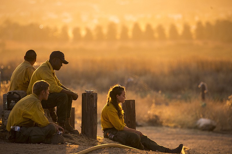 Firefighters rest during a wildfire in Yucaipa, Calif., Saturday, Sept. 5, 2020. Firefighters trying to contain the massive wildfires in Oregon, California and Washington state are constantly on the verge of exhaustion as they try to save suburban houses, including some in their own neighborhoods. (AP Photo/Ringo H.W. Chiu)