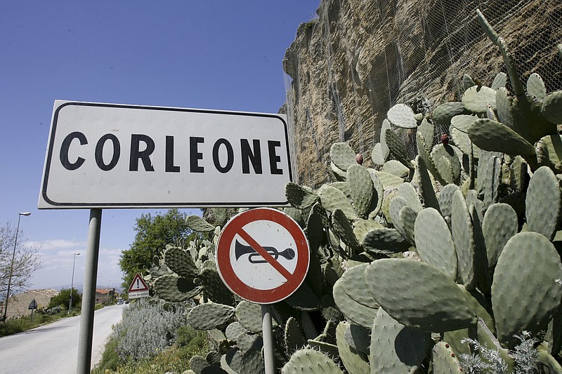FILE -- In this file photo taken on April 12, 2006, a road sign announces the town of Corleone, Italy. The Sicilian town of Corleone, made famous by the fictional Mafia clan in “The Godfather,” has ordered schools closed and a limited lockdown after a spate of coronavirus infections were tied to a big wedding there last week. (AP Photo/Luca Bruno)