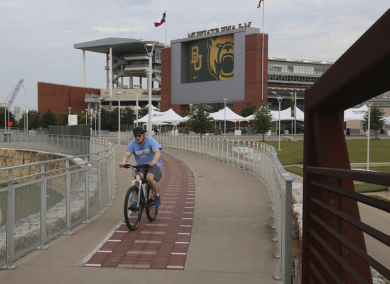 A bicyclist makes his way past Baylor University's McLane Stadium Thursday in Waco, Texas. Baylor’s season opener against Houston, scheduled less than a week ago, was one of two FBS NCAA college football games postponed Friday, the day before before they were supposed play. - Photo by Rod Aydelotte/Waco Tribune-Herald via The Associated Press