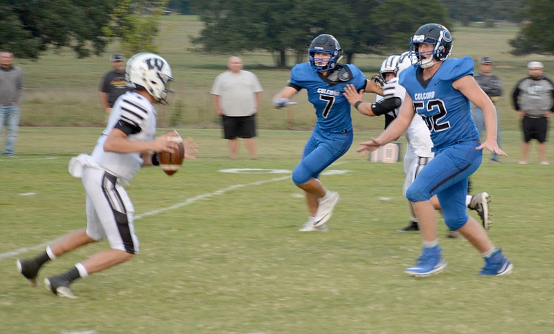 Graham Thomas/Siloam Sunday
Wyandotte quarterback, left, Brady Lofland looks to make a play as Colcord defenders Eyan Williams, No. 7, and Michael McCain, No. 52, converge on the play during Friday's game.