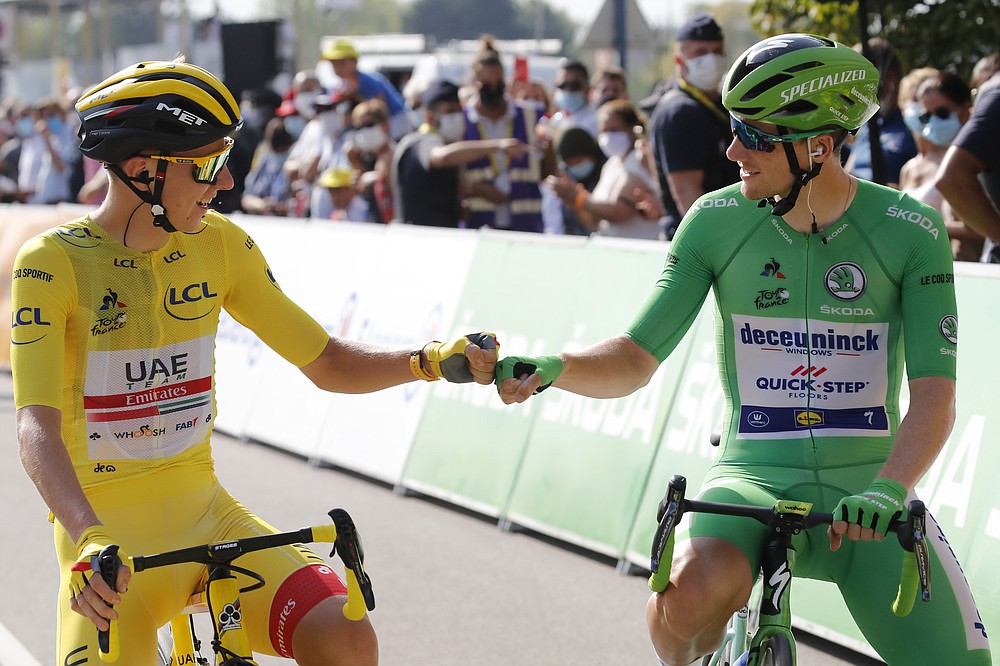 Slovenia's Tadej Pogacar, wearing the overall leader's yellow jersey, greets Sam Bennett of Ireland, wearing the best sprinter's green jersey, prior to the twenty-first and last stage of the Tour de France cycling race over 122 kilometers (75.8 miles), from Mantes-La-Jolie to Paris, France, Sunday, Sept. 20, 2020. (AP Photo/Christophe Ena)