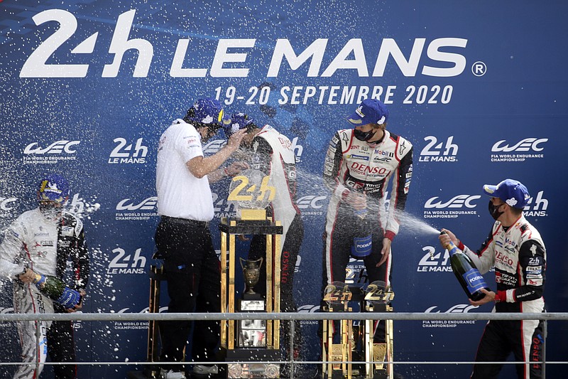 Drivers Sebastien Buemi of Switzerland, Kazuki Nakajima of Japan and Brendon Hartley of the Toyota Gazoo Racing Team spray champagne during the podium ceremony of the 88th 24-hour Le Mans endurance race, in Le Mans, western France, Sunday, Sept. 20, 2020. Due to coronavirus crisis, the race takes place without spectators. (AP Photo/David Vincent)