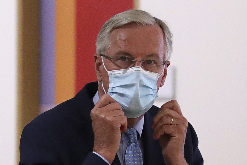 European Commission's Head of Task Force for Relations with the United Kingdom Michel Barnier puts on his protective face mask prior to meeting with European Council President Charles Michel at the EU Council building in Brussels, Friday, Sept. 18, 2020. (Yves Herman, Pool via AP)