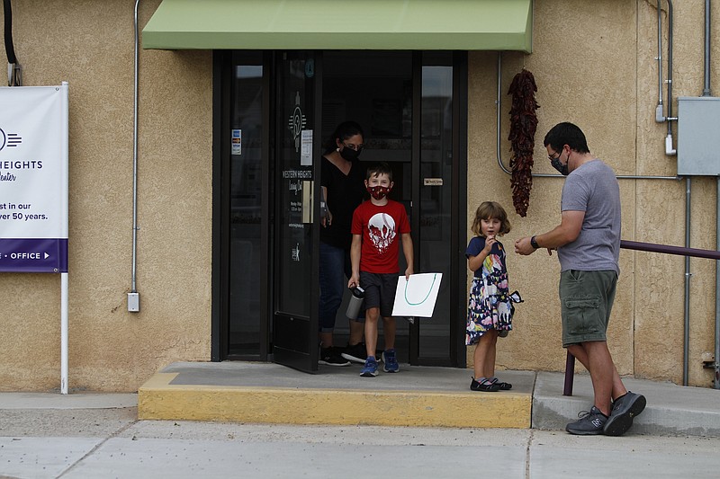 Public elementary school teachers Julia and Seth Hooper pick up their children Emry, 7, and Ivy, 4, on Monday, Aug. 10, at the Western Heights Learning Center in Albuquerque, New Mexico. The Hoopers said Emry will attend a private school at the center this fall because public schools won't be in person. Emry struggled with online learning in the spring and his parents were unable to help him while simultaneously teaching other online classes. (AP Photo/Cedar Attanasio)