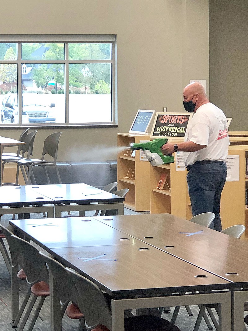 COURTESY PHOTO
Farmington High Principal Jon Purifoy uses a hydrostatic sprayer to sanitize the media center on Friday. All classrooms and high school facilities were sanitized Friday because of positive covid-19 cases on campus. On-site students had virtual learning on Friday and returned to their classrooms Monday.