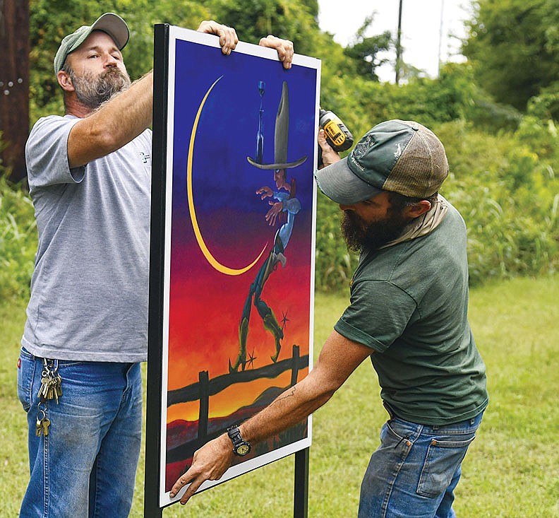 David Gillmore, left, and Chris Baber with the Hot Springs Parks and Trails Department install one of the 10 pieces in the “Art Moves” exhibit along the Hot Springs Creek Greenway Trail on Thursday. - Photo by Grace Brown of The Sentinel-Record