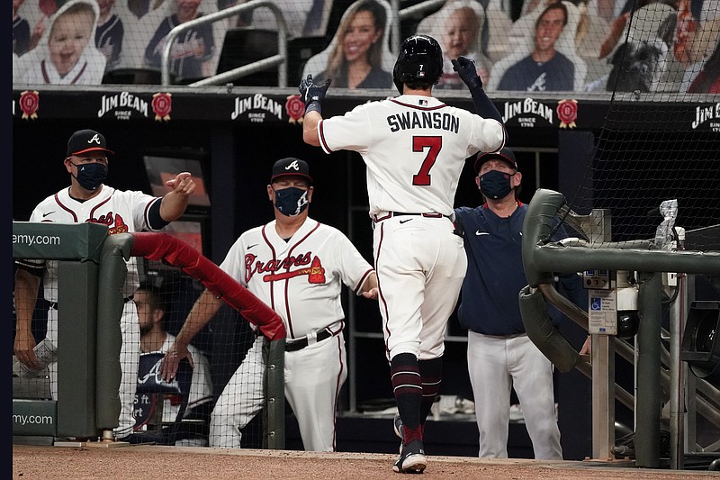 Atlanta Braves shortstop Dansby Swanson (7) is greeted by manager Brian Snitker and coach Walt Weiss, left, at the dugout after hitting a three-run home run in the fourth inning of a baseball game against the Miami Marlins Wednesday, Sept. 23, 2020, in Atlanta. (AP Photo/John Bazemore)