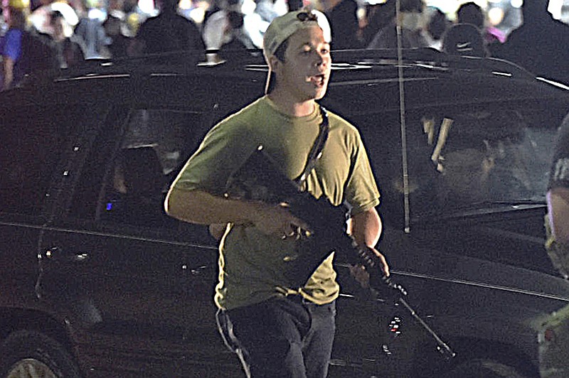 In this Tuesday, Aug. 25, 2020 file photo, Kyle Rittenhouse carries a weapon as he walks along Sheridan Road in Kenosha, Wis., during a night of unrest following the weekend police shooting of Jacob Blake. Rittenhouse was 17 when he was accused of killing two protesters days after Blake was shot by police in Kenosha. (Adam Rogan/The Journal Times via AP, File)