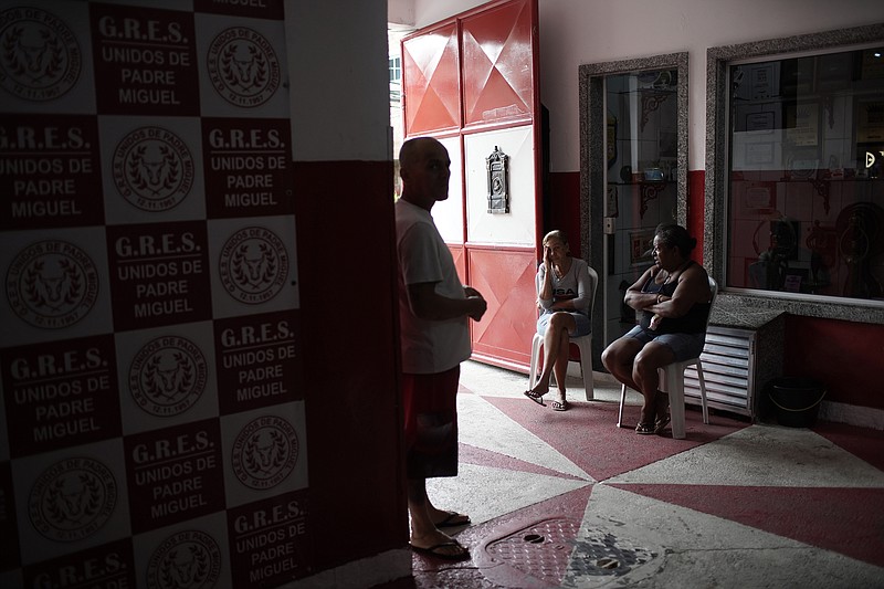 Members of the Unidos de Padre Miguel samba school chat at the "quadra" or court entrance, where float construction, costume sewing and dance rehearsals due to the new coronavirus pandemic have been canceled, in Rio de Janeiro, Brazil, Monday, Sept. 21, 2020. The city announced on Thursday, Sept. 24, said it has delayed its annual Carnival parade, saying the global spectacle cannot go ahead in February because of Brazil’s continued vulnerability to the new coronavirus pandemic. (AP Photo/Silvia Izquierdo)