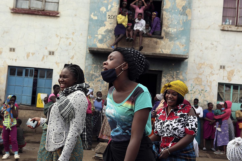 Women share a light moment while attending a social gathering in a poor neighbourhood in Mbare, Harare, Friday, Sept,18, 2020. As Zimbabwe's coronavirus infections decline, strict lockdowns designed to curb the disease are being replaced by a return to relatively normal life. The threat has eased so much that many people see no need to be cautious, which has invited complacency. (AP Photo/Tsvangirayi Mukwazhi)