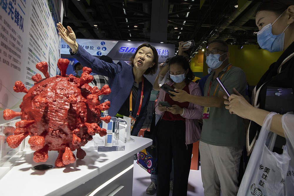 An employee answers questions from the public near samples of a COVID-19 vaccine produced by Sinopharm subsidiary CNBG are displayed during a trade fair in Beijing on Sept. 6, 2020. State-backed Sinopharm's subsidiary CNBG has injected 350,000 people outside its clinical trials for COVID-19 vaccine, which have about 40,000 people enrolled. It's a highly unusual move that raises ethical and safety questions, as companies and governments worldwide race to develop a vaccine that will stop the spread of the new coronavirus. (AP Photo/Ng Han Guan)