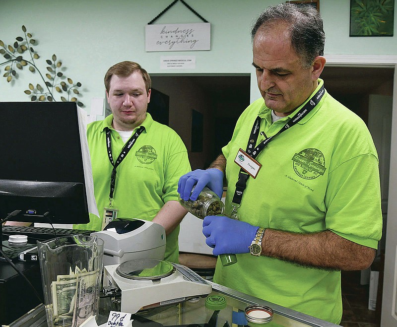 NOTE: FOR SENTINEL-RECORD STORY Owner of Green Springs Medical Marijuana Dispensary Dragan Vicentic, right,  and budtender Austin Briggs demonstrates how they package the medical marijuana they sell on Thursday, March 26, 2020. -Photo by Grace Brown of The Sentinel-Record.