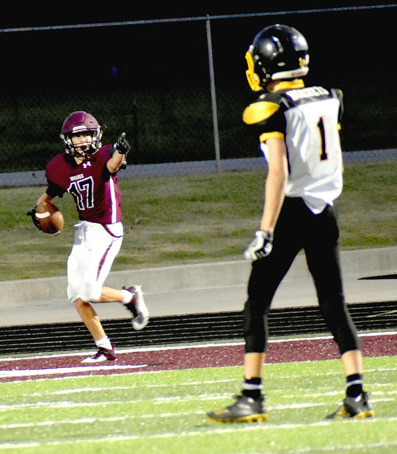 MARK HUMPHREY  ENTERPRISE-LEADER/Lincoln freshman Jace Birkes points back at quarterback Drew Moore (not in photo) after catching the a deep touchdown pass in the junior Wolves' 36-16 win over Hackett Thursday at Wolfpack Stadium. The nearest defender on the play is 15 yards away.