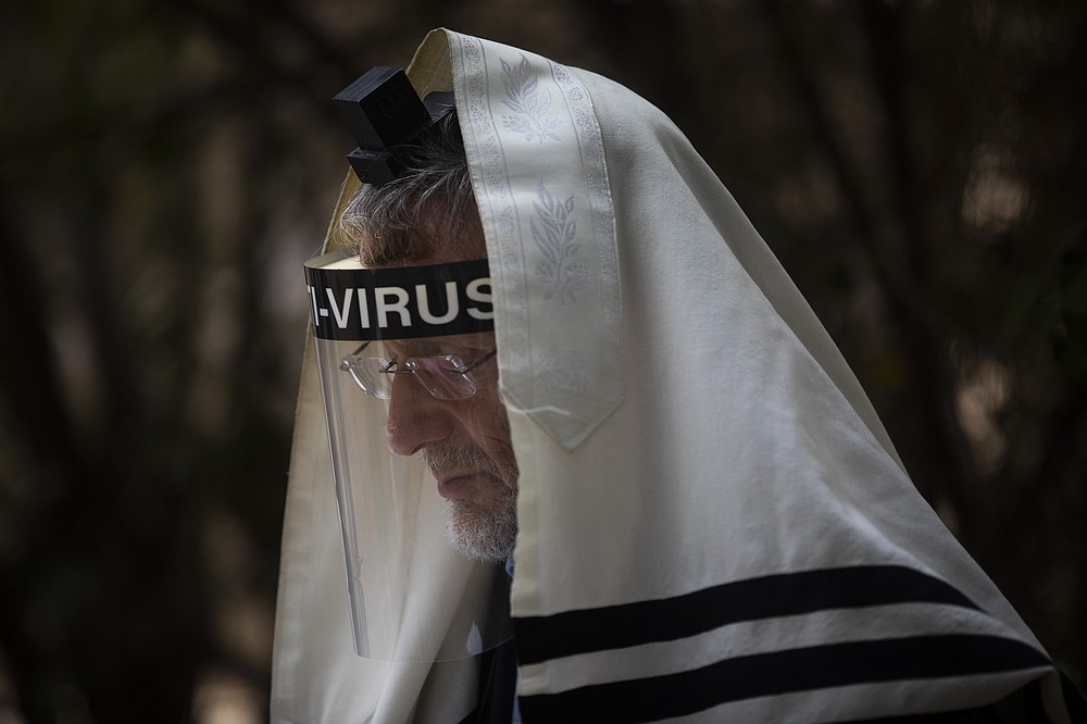 An ultra-Orthodox Jewish man wears a face mask during a morning prayer next to his house as synagogues are limited to twenty people due to the coronavirus pandemic, in Bnei Brak, Israel, Thursday, Sept 24, 2020. For Israel's ultra-Orthodox Jews, coronavirus restrictions have raised numerous questions about how to maintain their religious lifestyle during the outbreak. A religious publisher in Jerusalem released a book in July with over 600 pages of guidance from 46 different rabbis. (AP Photo/Oded Balilty)
