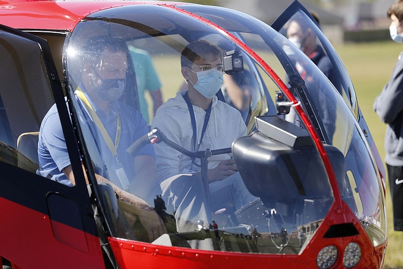 Lukas Crosom, a senior at Har-Ber High School and student in the aviation course, sits in the cockpit of a Robinson R44 Raven 1, Tuesday, September 29, 2020, with assistant principal Patrick Scott at the school in Springdale. The helicopter was flown in by ARH Aviation to demonstrate the components and discuss the flying characteristics of the aircraft to the aviation students. Check out nwaonline.com/200930Daily/ and nwadg.com/photos for a photo gallery.(NWA Democrat-Gazette/David Gottschalk)