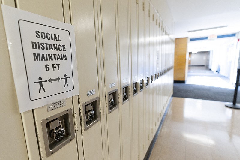 FILE - In this Aug. 28, 2020, file photo, a sign that reads "Social Distance Maintain 6 ft" is posted on student lockers at a school in Baldwin, N.Y. The coronavirus is infecting a rising number of American children and teens in a trend authorities say appears driven by school reopenings and the resumption of sports, playdates and other activities. (AP Photo/Mark Lennihan, File)