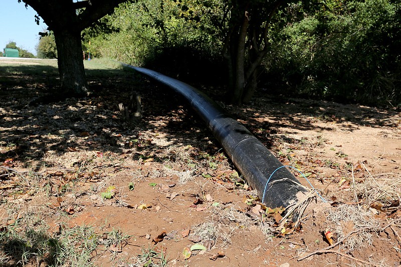 An eight inch continual polyethylene pipe from the former failing Bethel Heights water treatment plant to a connection  with a Springdale sewer line is visible Tuesday, September 29, 2020, as it comes out of the ground after passing under a road. Check out nwaonline.com/200930Daily/ and nwadg.com/photos for a photo gallery.(NWA Democrat-Gazette/David Gottschalk)