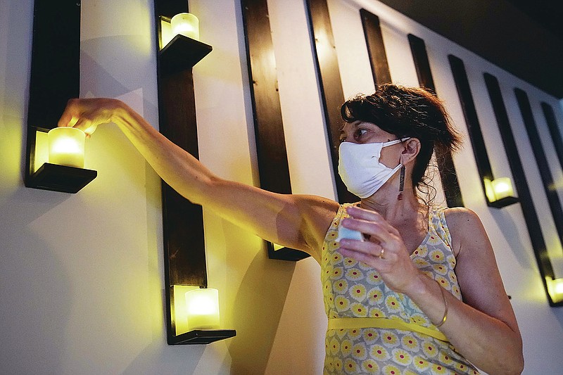 Mama Fox owner Samantha DiStefano installs electric tea lights in preparation for indoor dining at her bar and restaurant, Tuesday, Sept. 29, 2020, in the Bedford-Stuyvesant neighborhood of Brooklyn, in New York. Some lights were dead because they haven't been used in six months when Mama Fox closed during the viral pandemic. New York restaurants may reopen for indoor dining on Wednesday, but with capacity restricted to 25%. "It's baby steps. The 25% gives you the opportunity to dip your toe in," DiStefano said. (AP Photo/Kathy Willens)