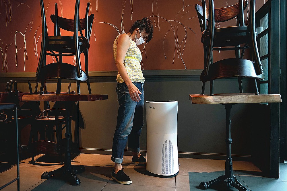 Mama Fox owner Samantha DiStefano looks at an air purifier she'll need when she opens the indoor portion of her restaurant and bar to patrons, Tuesday, Sept. 29, 2020, in New York, as she continues preparation for indoor dining. DiStefano doesn't plan on opening Wednesday, when indoor dining will be permitted in New York for the first time since March, but said she may try serving patrons at tables near the restaurant's floor-to-ceiling windows where diners can have fresh air while eating. (AP Photo/Kathy Willens)