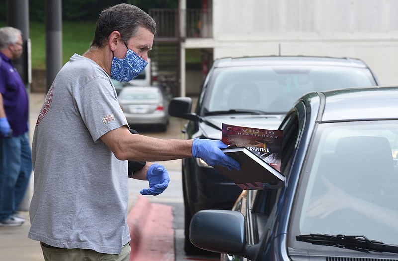 Stephen Teague, a photography teacher at Fayetteville High School, helps distribute yearbooks with a special supplement Covid-19 Heartbreak to seniors Monday during a curbside pick-up and drop off at the school. Seniors were able to pick-up yearbooks, their caps and gowns, school records and also drop off textbooks and fine arts equipment. The pick-up and drop off will continue today from 9:00 a.m. to 2:00 p.m. for seniors. Visit nwaonline.com/200505Daily/ and nwadg.com/photos for a photo gallery.
(NWA Democrat-Gazette/David Gottschalk)