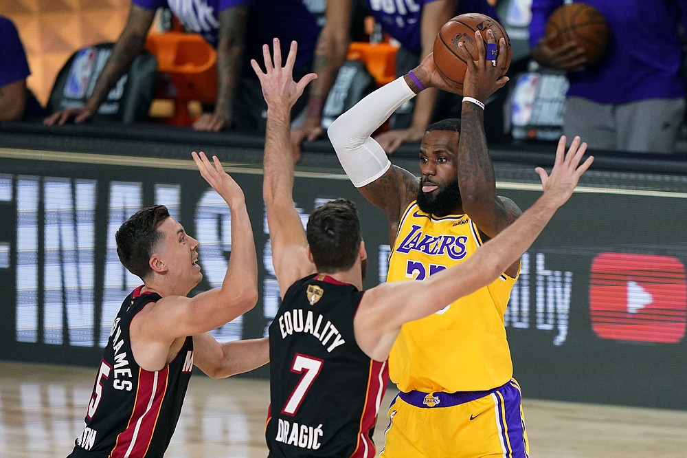 Los Angeles Lakers' LeBron James, right, looks to pass while covered by Miami Heat's Duncan Robinson, left, and Goran Dragic (7) during the first half of Game 1 of basketball's NBA Finals Wednesday, Sept. 30, 2020, in Lake Buena Vista, Fla. (AP Photo/Mark J. Terrill)