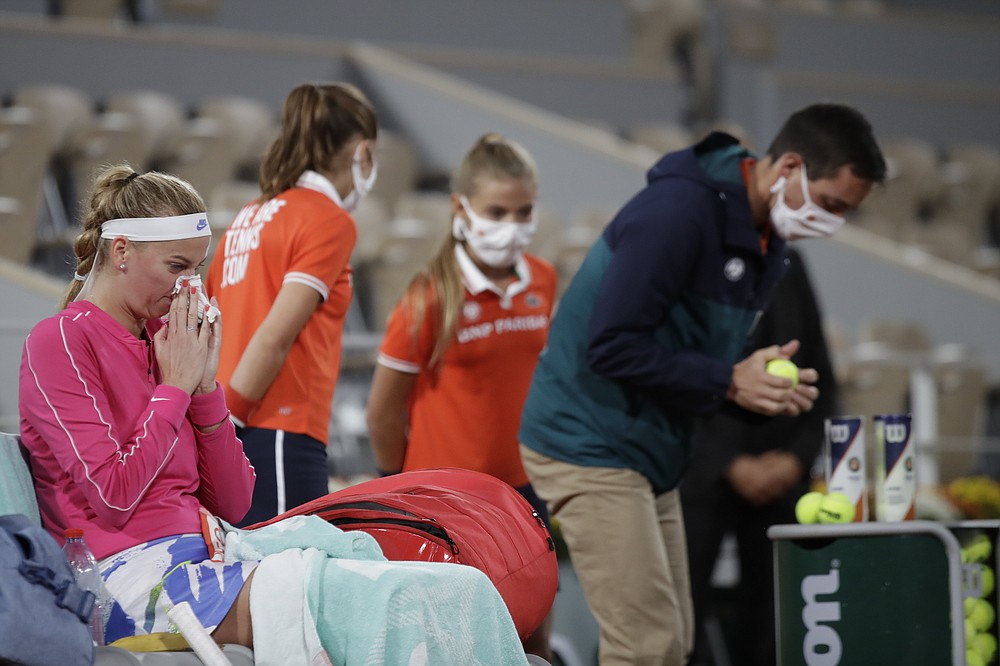 Petra Kvitova of the Czech Republic wipes her nose as an official, right, tests the balls in the first round match of the French Open tennis tournament against France's Oceane Dodin at the Roland Garros stadium in Paris, France, Monday, Sept. 28, 2020. (AP Photo/Alessandra Tarantino)