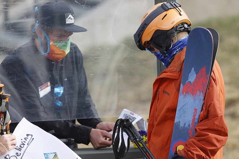 An employee is protected by a plexiglass shield while processing a skier at the reopening of Arapahoe Basin Ski Resort, which closed in mid-March to help in the effort to stop the spread of the new coronavirus, in a Wednesday, May 27, 2020 file photo, in Keystone, Colo. An executive order signed y President Donald Trump that temporarily bans a wide variety of foreign visas has thrown another obstacle in the path of ski resorts as they try to hire enough temporary workers to fill crucial jobs in the era of COVID-19. (AP Photo/David Zalubowski, File) story.lead_photo.caption