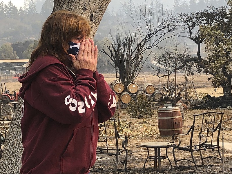 Nikki Conant cries as she looks at the debris of her home and business, "Conants Wine Barrel Creations," after the Glass/Shady fire completely engulfed it, Wednesday, Sept. 30, 2020, in Santa Rosa, Calif. The Conants escaped with their lives, which we are grateful for, but they barely made it out with the clothes on their backs in the wake of the fire. The Glass and Zogg fires are among nearly 30 wildfires burning in California. (AP Photo/Haven Daley)