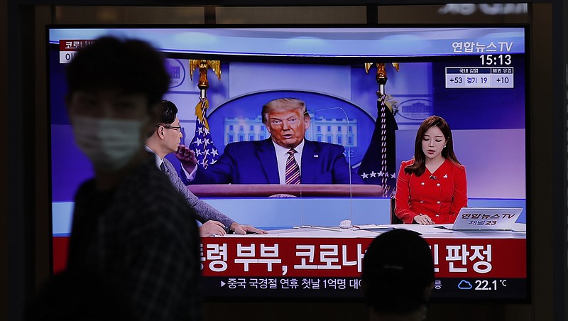 A man wearing a face mask walks near a TV screen reporting about U.S. President Donald Trump and first lady Melania Trump during a news program with a file image of Trump at the Seoul Railway Station in Seoul, South Korea, Friday, Oct. 2, 2020. Trump said early Friday that he and Melania Trump have tested positive for the coronavirus, a stunning announcement that plunges the country deeper into uncertainty just a month before the presidential election. The Korean letters read: "President Donald Trump and first lady Melania Trump tested positive for COVID-19." (AP Photo/Lee Jin-man) story.lead_photo.caption