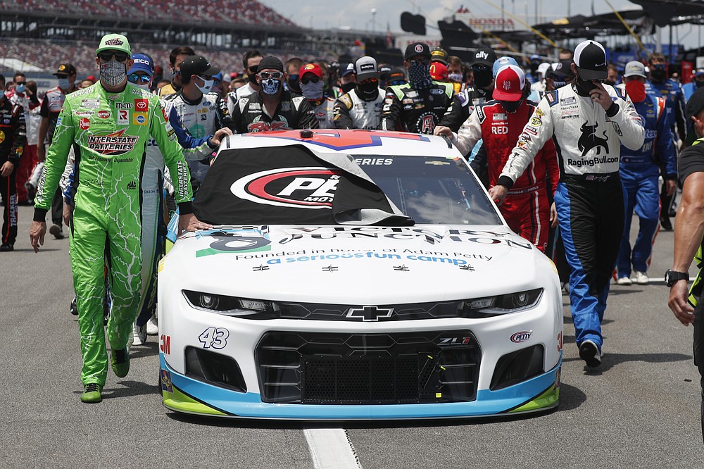 FILE - In this June 22, 2020, file photo, NASCAR drivers Kyle Busch, left, and Corey LaJoie, right, join other drivers and crews as they push the car of Bubba Wallace to the front of the field prior to the start of the NASCAR Cup Series auto race at the Talladega Superspeedway in Talladega Ala. The Cup Series returns to Talladega on Sunday. (AP Photo/John Bazemore, File)