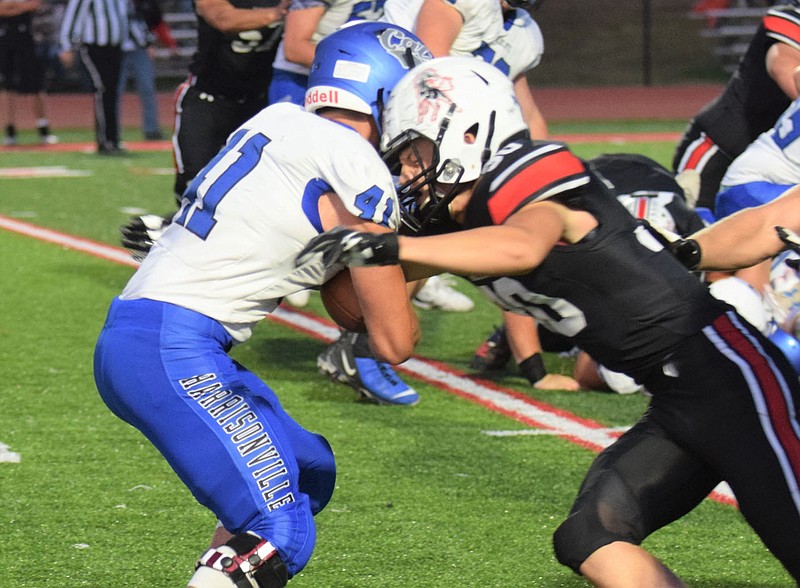 RICK PECK/SPECIAL TO MCDONALD COUNTY PRESS McDonald County linebacker Andrew Watkins (right) stops Harrisonville running back Joshua Pesek for a short gain during the Mustangs' 28-14 loss on Oct. 2 at McDonald County High School.