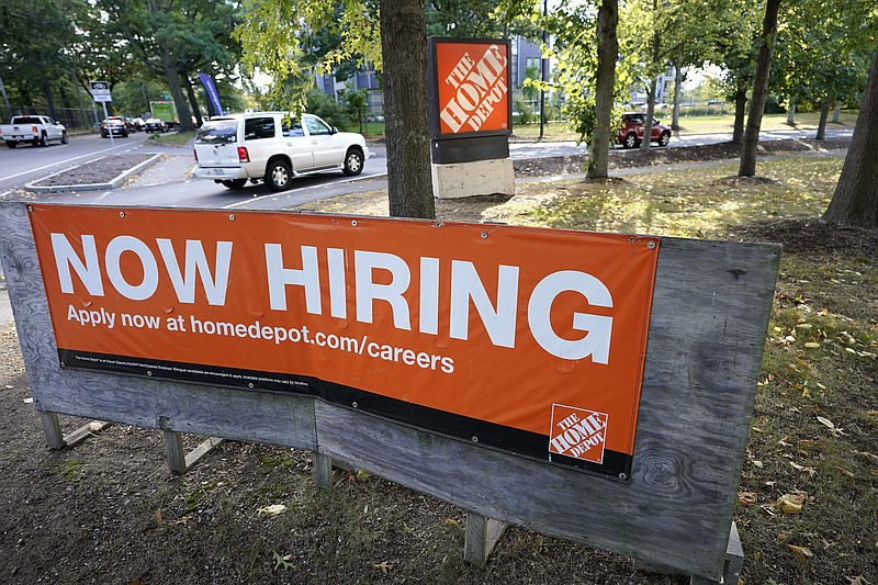 Vehicles drive past a now hiring sign as they enter a parking lot for a Home Depot store location, Wednesday, Sept. 30, 2020, in Boston. The number of Americans seeking unemployment benefits declined last week to a still-high 837,000, evidence that the economy is struggling to sustain a tentative recovery that began this summer.  (AP Photo/Steven Senne)