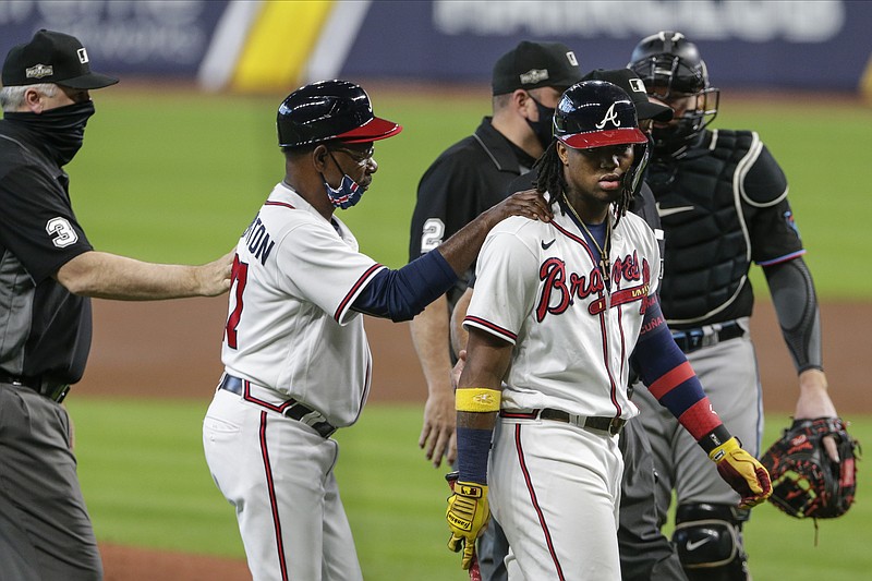 Atlanta Braves third base coach Ron Washington consoles Ronald Acuna Jr., center, during the third inning in Game 1 of a baseball National League Division Series against the Miami Marlins Tuesday, Oct. 6, 2020, in Houston. (AP Photo/Michael Wyke)