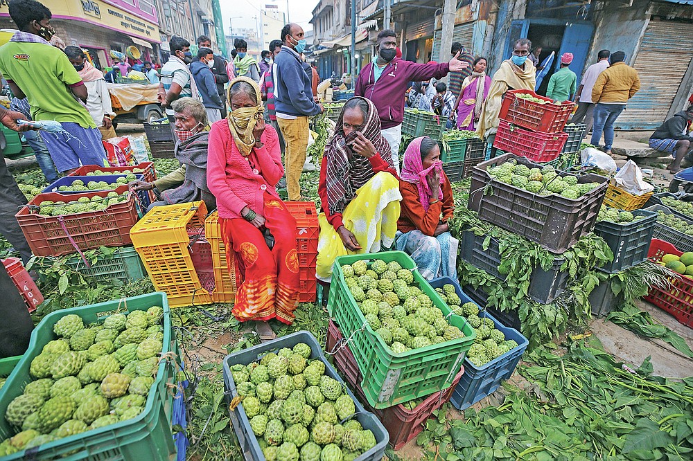 Fruit vendors cover their faces as a precaution against the coronavirus and wait for buyers at a wholesale market in Bengaluru, India, Thursday, Sept. 24, 2020. In the April-June quarter, government figures show, activity in trade, hotels, transport, construction and communication declined by nearly half from a year earlier. Manufacturing contracted by about 40%. Despite the strains, there are some bright spots. Agriculture overall is growing at a 3.4% pace. With good monsoon rains, India might attain a record of 301 million metric tons of food-grain output, including wheat, rice, oil seeds, lentils and mustard, in the 2020-21 financial year, 4 million metric tons more than in 2019-20. (AP Photo/Aijaz Rahi)