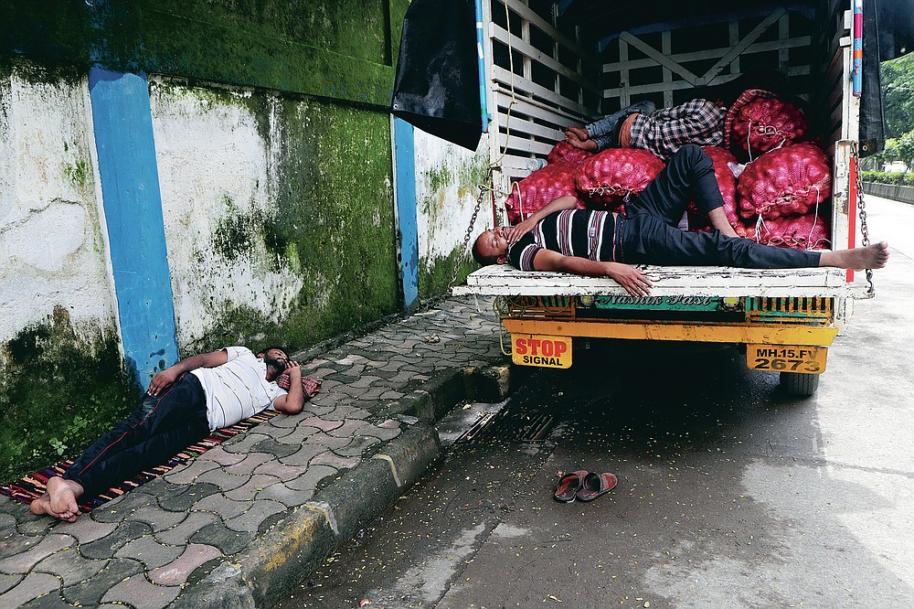 People sleep by a truck carrying vegetables in Mumbai, India, Friday, Sept. 25, 2020. In the April-June quarter, government figures show, activity in trade, hotels, transport, construction and communication declined by nearly half from a year earlier. Manufacturing contracted by about 40%. Despite the strains, there are some bright spots. Agriculture overall is growing at a 3.4% pace. With good monsoon rains, India might attain a record of 301 million metric tons of food-grain output, including wheat, rice, oil seeds, lentils and mustard, in the 2020-21 financial year, 4 million metric tons more than in 2019-20. (AP Photo/Rajanish Kakade)