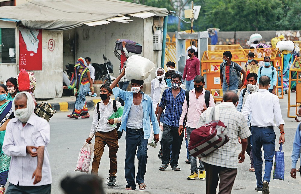 Migrant workers return with their belongings to look for work in New Delhi, India, Tuesday, Aug. 18, 2020. The lockdown imposed in late March cost more than 10 million impoverished migrant workers their jobs in the cities. Many made grueling journeys back to their hometowns and villages. Now they face the ordeal of trying to get back to their factory jobs. The government began easing a stringent two-month-long lockdown in June, but business is only a quarter to a fifth of usual and customers are scarce, said Praveen Khandelwal, general secretary of the Confederation of All India Traders. (AP Photo/Manish Swarup)