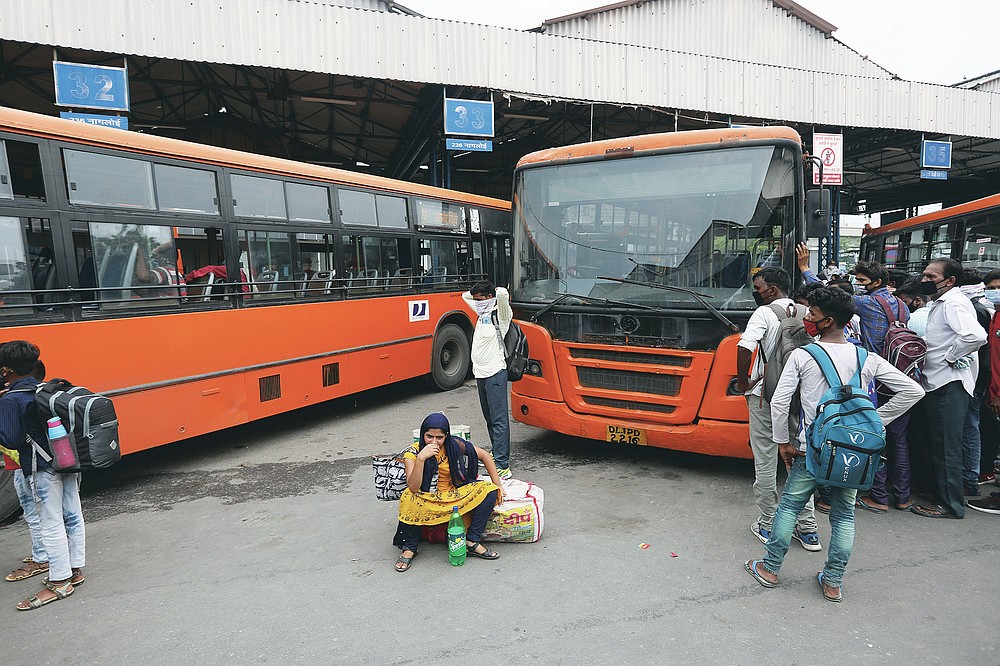 Migrant workers wait for transportation after having their COVID-19 tests done upon arrival in New Delhi, India, Tuesday, Aug. 18, 2020. The lockdown imposed in late March cost more than 10 million impoverished migrant workers their jobs in the cities. Many made grueling journeys back to their hometowns and villages. Now they face the ordeal of trying to get back to their factory jobs. (AP Photo/Manish Swarup)