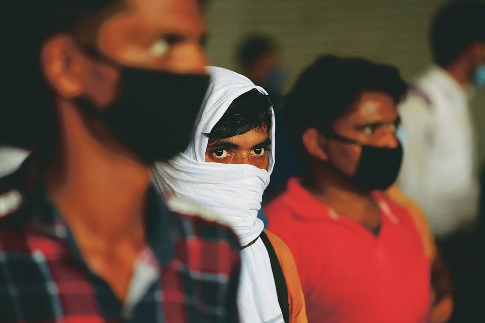 Migrant workers wait to get their COVID-19 tests done as they return to look for jobs in New Delhi, India, Tuesday, Aug. 18, 2020. The lockdown imposed in late March cost more than 10 million impoverished migrant workers their jobs in the cities. Many made grueling journeys back to their hometowns and villages. Now they face the ordeal of trying to get back to their factory jobs. India's pandemic assistance has amounted to only about 1% of its GDP, Nobel laureate Abhijit Banerjee said, compared with the U.S.'s package in March of about 10% of its GDP. (AP Photo/Manish Swarup)