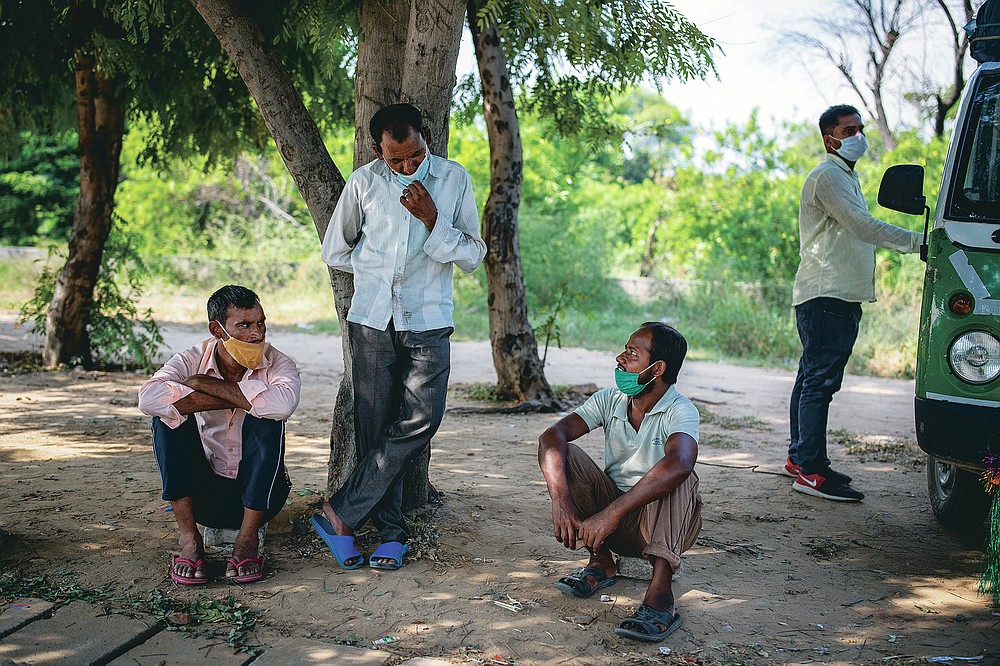 Migrant workers Ram Ratan, center standing, and Mansoor Ansari, seated right, talk sitting by the side of a road as they look for jobs in Manesar, India, Tuesday, Sept. 22, 2020. “There is almost no work,” said Ratan, 46, who was working in a printing company before he returned to his home village in April. Ansari and Ratan are among hundreds of workers who wait every day on what is called  a “labor roundabout,” in an industrial area, hoping to get picked up by employers. Before the pandemic lockdown, Ansari had a steady job at a garment factory in the industrial town of Manesar near New Delhi, earning $200 a month, he said. (AP Photo/Altaf Qadri)