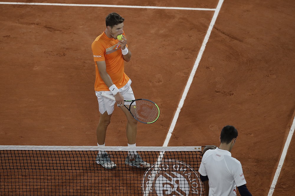 Spain's Pablo Carreno Busta bites the ball when switching sides with Serbia's Novak Djokovic, bottom right, in the quarterfinal match of the French Open tennis tournament at the Roland Garros stadium in Paris, France, Wednesday, Oct. 7, 2020. (AP Photo/Alessandra Tarantino)